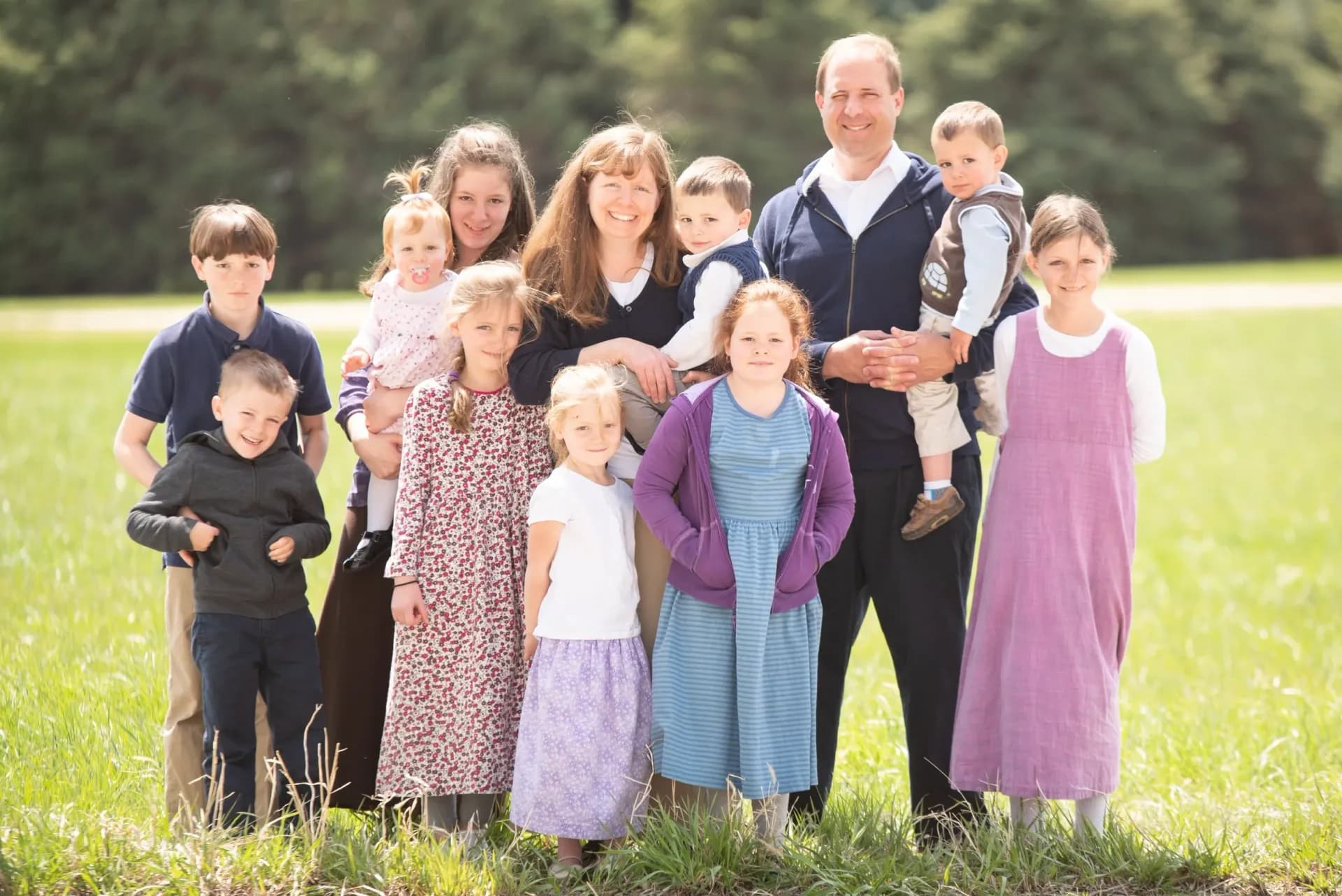 A picture of an elder and his large family standing in a field next to Sharon RP Church
